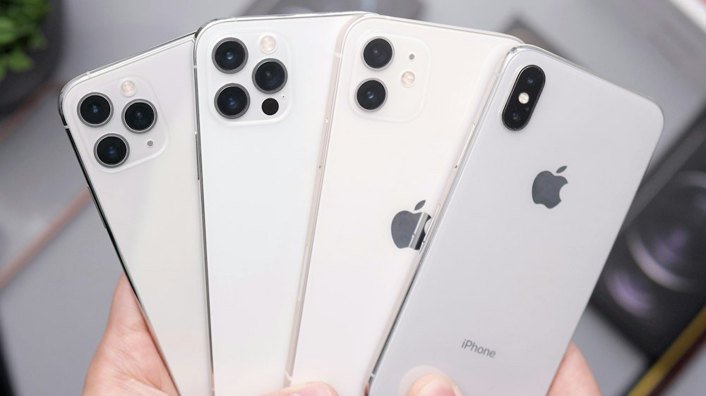 Hand holding a fan of white iPhones